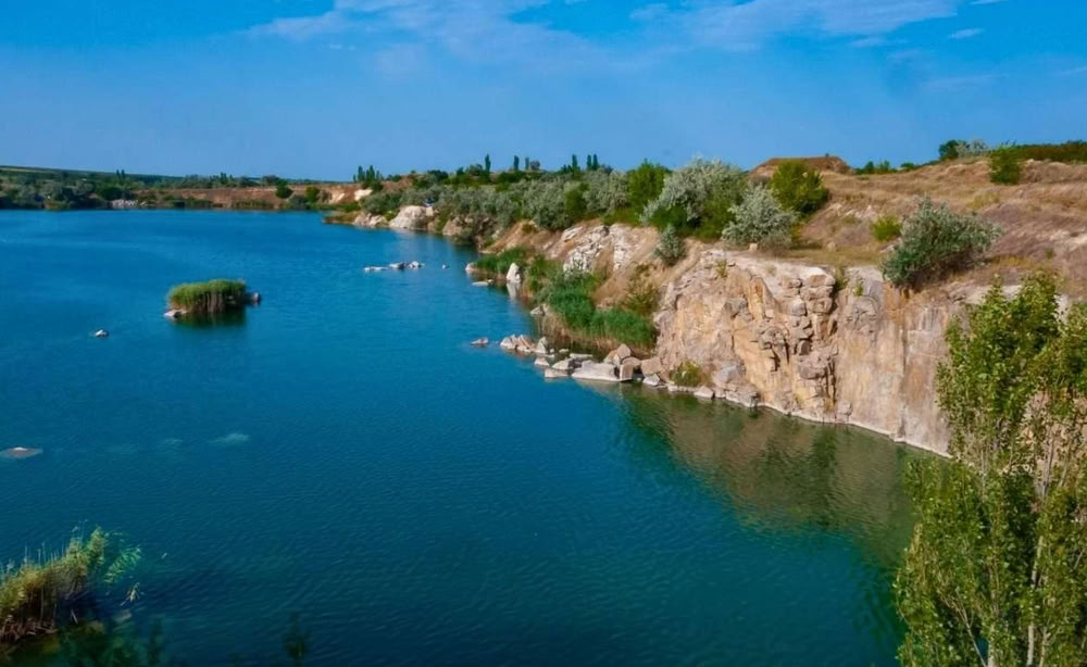 відпочинок під Києвом у лісі — скелястий берег та прозора вода кар'єру серед природного ландшафту